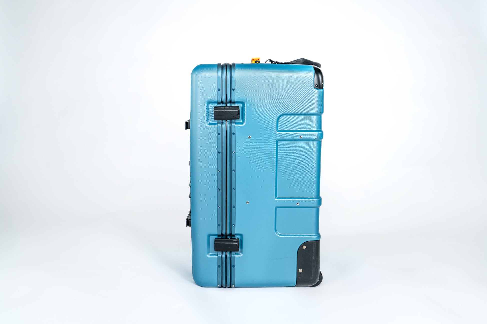 Side view of the closed blue Belonging LifeLocker Founders Bundle showing molded exterior panels, front handle, and black attachment straps on a white studio background.